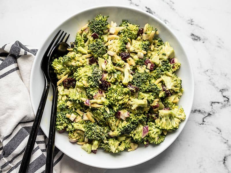 This crunchy, sweet, tangy, and creamy Honey Mustard Broccoli Salad only takes minutes to makes the perfect summer side dish. BudgetBytes.com Finished honey mustard broccoli salad in a bowl, seen from above, with black fork and spoon in the side of the bowl.