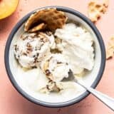 Overhead view of one bowl of no churn balsamic peach ice cream with waffle cone and a fresh peach on the side.