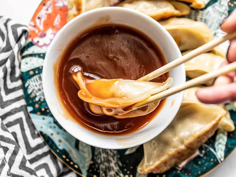 This Simple Sweet and Sour Sauce can be whipped up in minutes with only a few pantry staples, so you don't have to keep another condiment in your fridge! BudgetBytes.com Close up of a dumpling being dipped into a bowl of Simple Sweet and Sour Sauce
