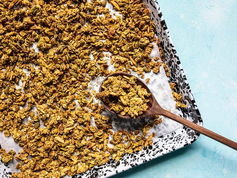 Aquafaba (the leftover starchy water from canned beans) makes this Oil Free Granola super crunchy without using excessive amounts of oil and sugar! BudgetBytes.com A sheet pan full of Super Crunchy Oil Free Granola with a large wooden spoon scooping it up.