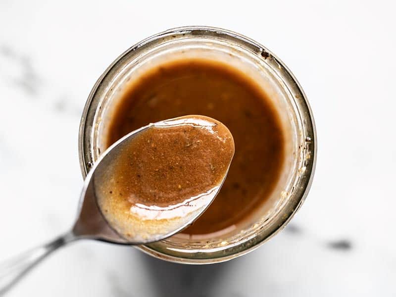 This super simple homemade balsamic vinaigrette is perfect for all your green salads and pasta salads and has several options for customizing! BudgetBytes.com Finished homemade balsamic vinaigrette on a spoon over the mouth of the mason jar