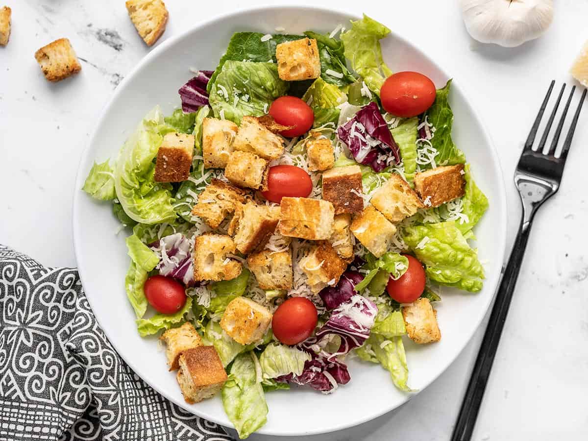 Homemade croutons are a super easy to make, and their crispy, crunchy texture takes any soup or salad to the next level! Only five ingredients! BudgetBytes.com Overhead view of a salad in a bowl topped with homemade croutons.