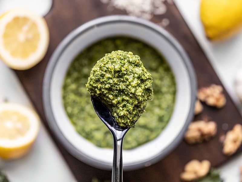 Making a small batch of kale pesto is a great way to use leftover kale. This flavorful pesto is great on sandwiches, in soups, dips, and more! BudgetBytes.com Close up of Kale Pesto on a spoon with the bowl in the background.