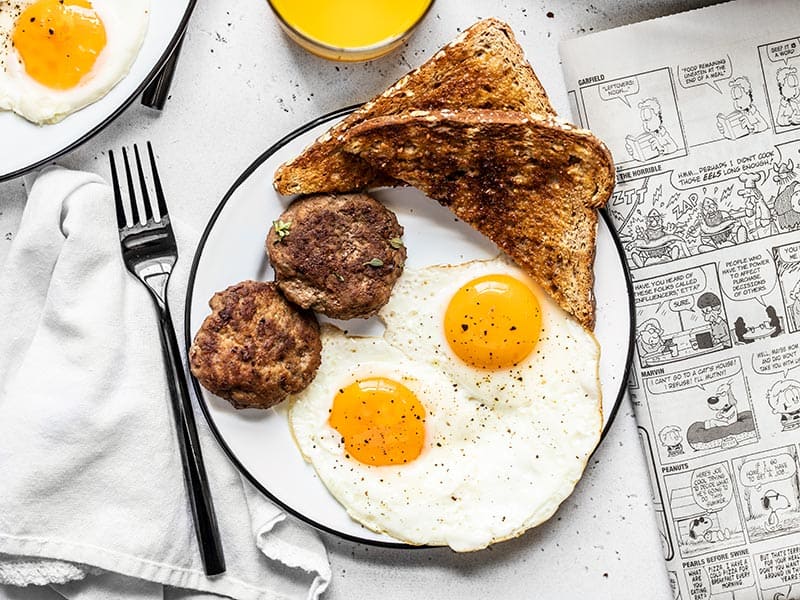 Maple Sage Breakfast Sausage is an easy way to make your weekend breakfast a little extra special, or to meal prep your breakfast protein for the week! BudgetBytes.com A breakfast plate with eggs, toast, and maple sage breakfast sausage, next to a newspaper and glass of orange juice.