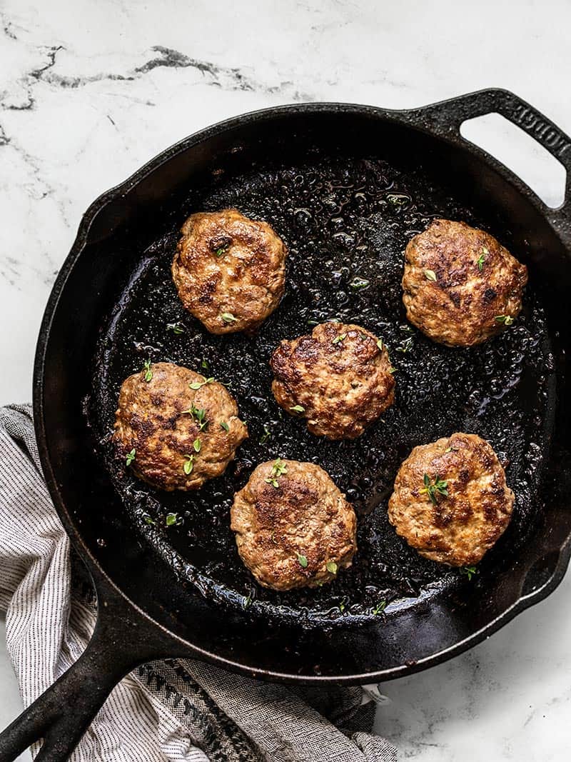 Maple Sage Breakfast Sausage is an easy way to make your weekend breakfast a little extra special, or to meal prep your breakfast protein for the week! BudgetBytes.com Overhead of a cast iron skillet with five cooked Maple Sage Breakfast Sausage patties