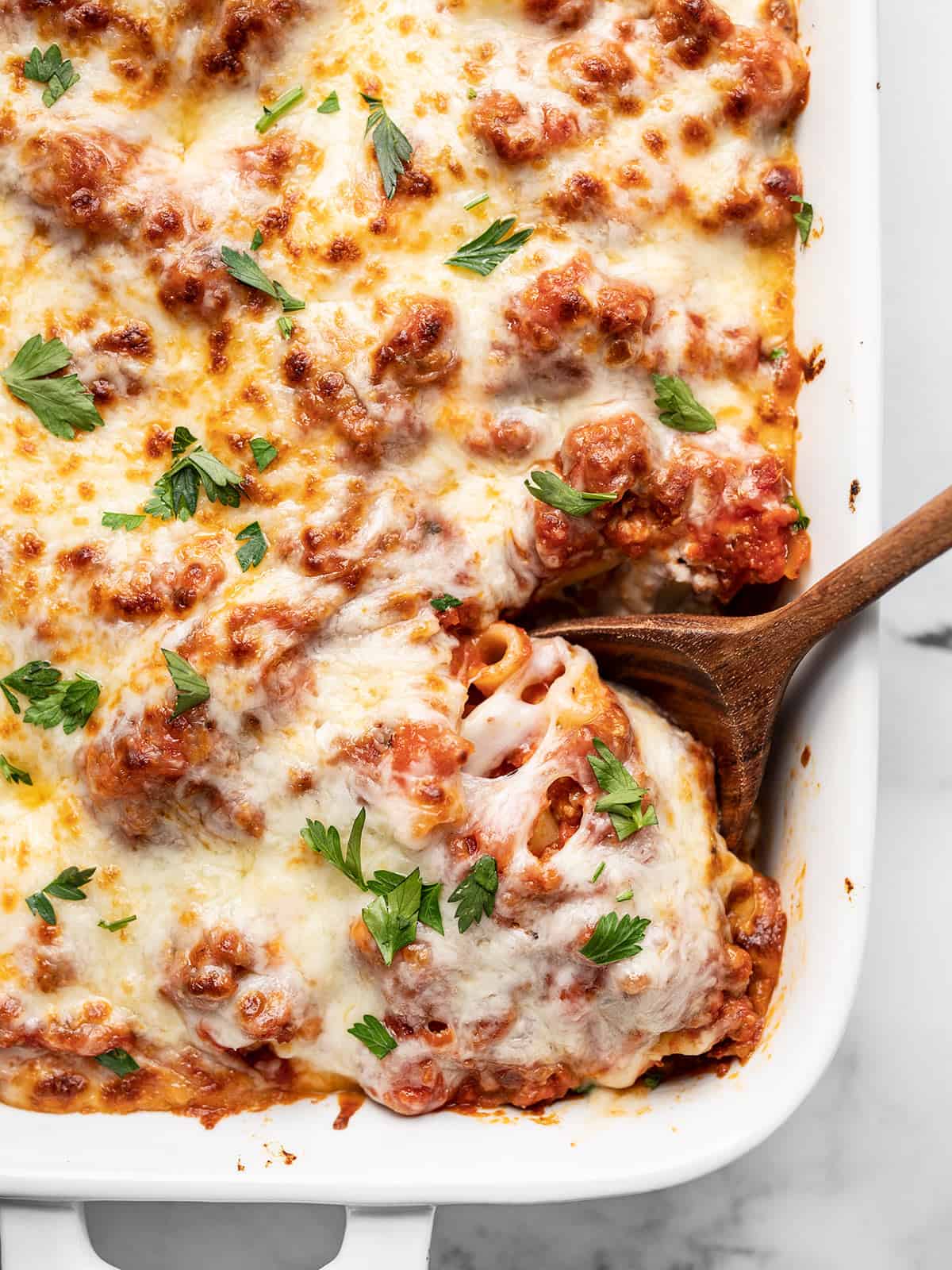 Like a freeform lasagna, this Baked Ziti has layers of pasta, homemade red sauce with Italian sausage, and three types of melty cheese! BudgetBytes.com Overhead view of baked ziti being scooped out of the casserole dish.