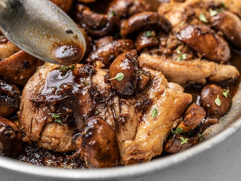 A quick buttery balsamic pan sauce brings a ton of flavor to these Balsamic Chicken and Mushrooms without a lot of work. Perfect for weeknight dinners! BudgetBytes.com Close up of the balsamic pan sauce being drizzled over the chicken and mushrooms in the skillet