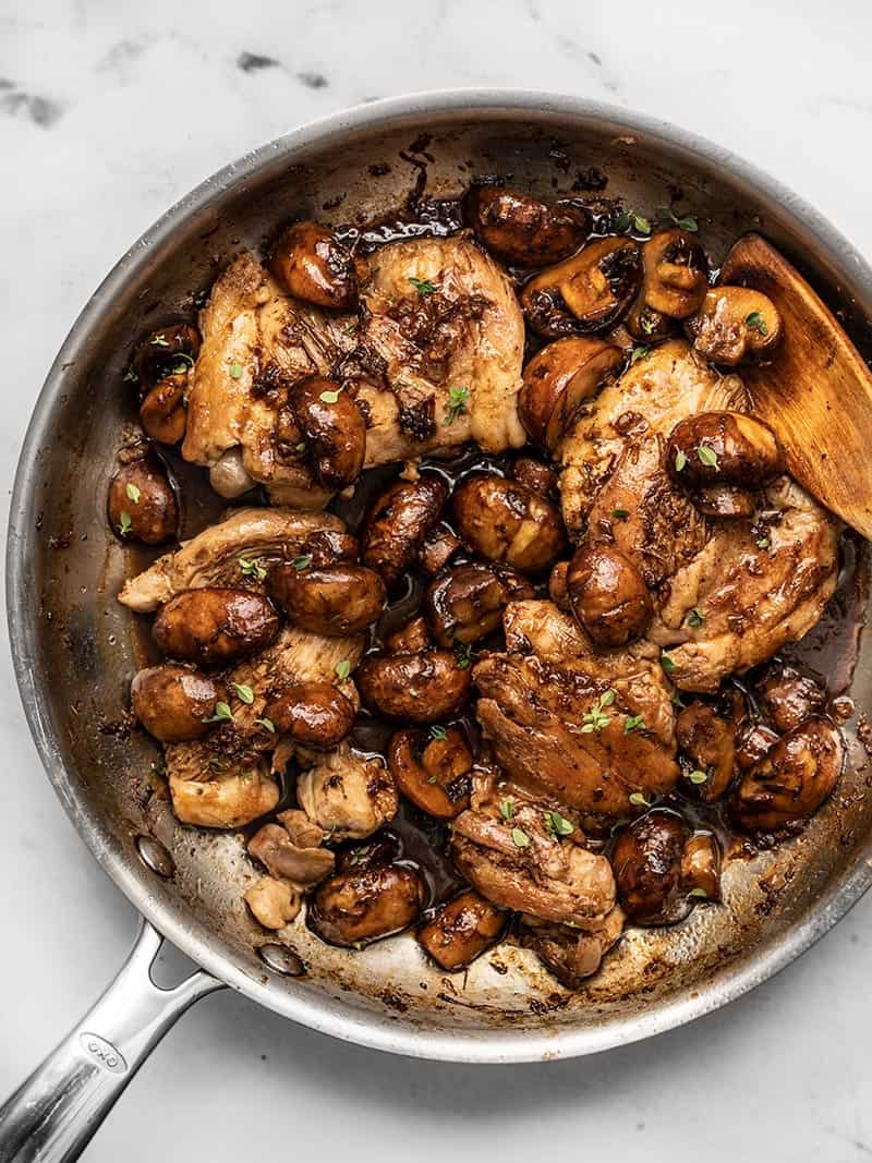 A quick buttery balsamic pan sauce brings a ton of flavor to these Balsamic Chicken and Mushrooms without a lot of work. Perfect for weeknight dinners! BudgetBytes.com Overhead view of a skillet full of Balsamic Chicken and Mushrooms with a wooden spoon in the side