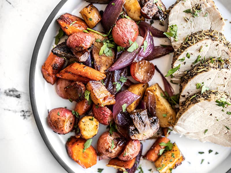 These sweet and savory caramelized Balsamic Roasted Vegetables are an easy and elegant all-purpose side dish that you'll want to make over and over! BudgetBytes.com Balsamic roasted vegetables on a plate with roasted pork.
