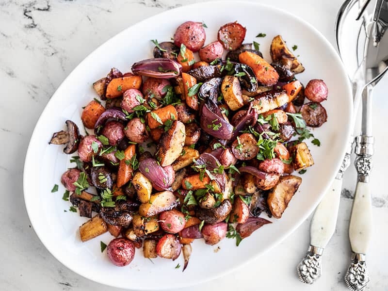 These sweet and savory caramelized Balsamic Roasted Vegetables are an easy and elegant all-purpose side dish that you'll want to make over and over! BudgetBytes.com Balsamic roasted vegetables plated on a platter with chopped parsley on top.