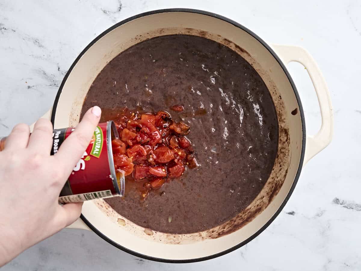 A can of fire roasted tomatoes added to a pot of black bean soup.