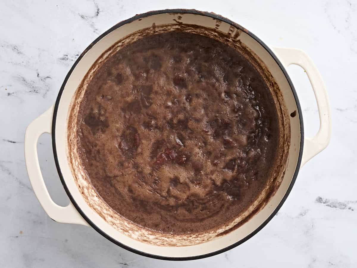 A bubbling black bean soup in a soup pot which has come to a boil.