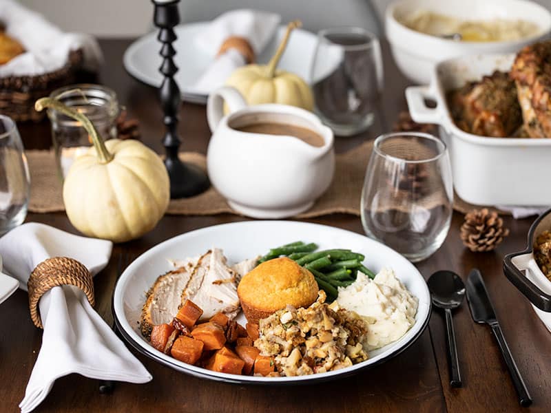 This simple guide for How to Make an Easy Thanksgiving Dinner for Beginners includes an easy menu for six, and full two-day prep schedule! BudgetBytes.com Close up view of a full Thanksgiving dinner plate with other dishes on the table in the background