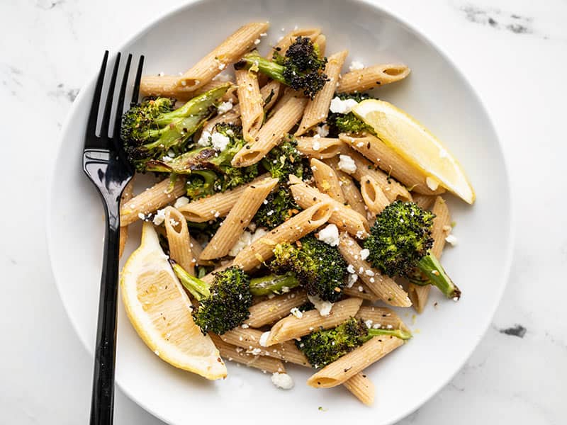 Roasted Broccoli Pasta with Lemon and Feta is an incredibly simple pasta dish with big flavors. An easy, fast, and delicious weeknight dinner! BudgetBytes.com A bowl full of Roasted Broccoli Pasta with lemon and feta and a black fork on the left side