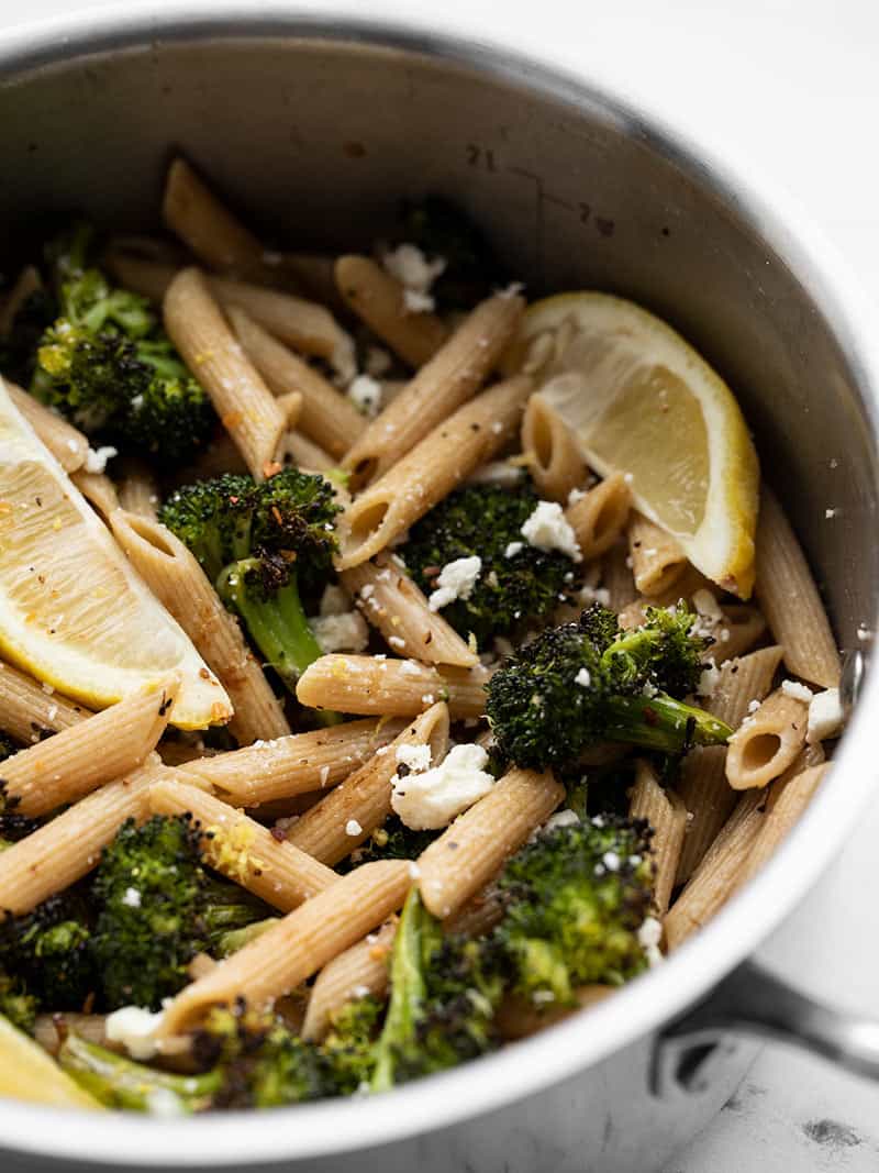 Roasted Broccoli Pasta with Lemon and Feta is an incredibly simple pasta dish with big flavors. An easy, fast, and delicious weeknight dinner! BudgetBytes.com Front view of a pot full of Roasted Broccoli Pasta with Lemon and feta, garnished with lemon wedges