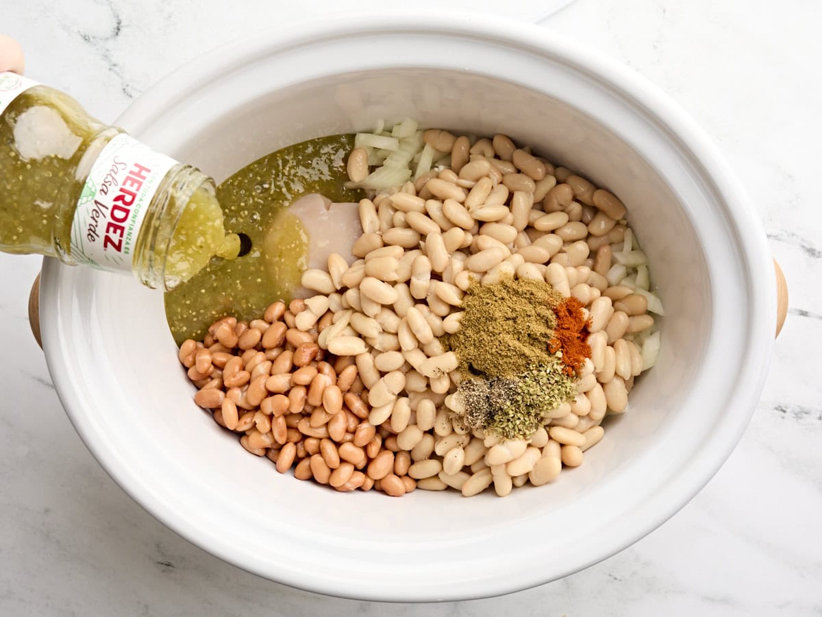 Canned beans, salsa verde, and seasonings added to crockpot.