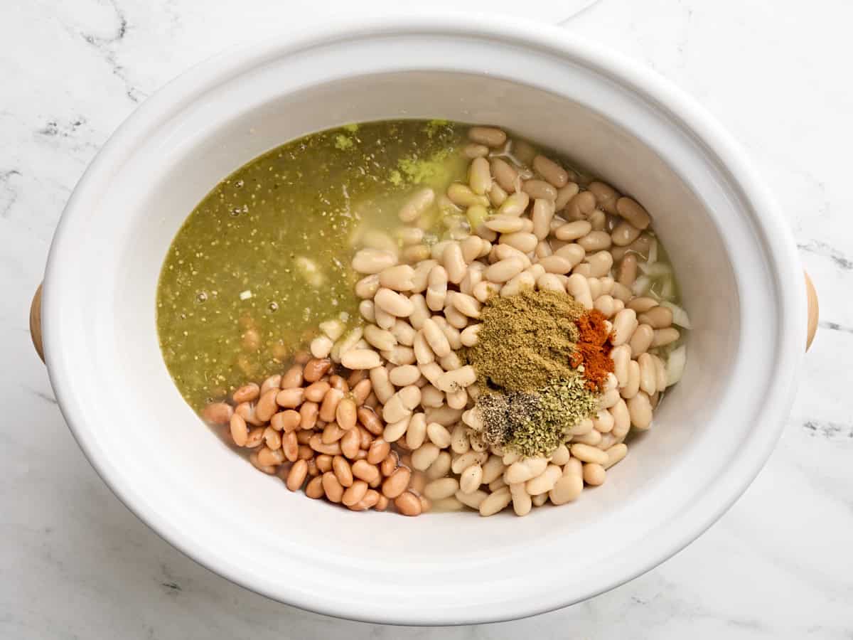 Stock added to a crockpot with the other ingredients for slow cooker white chicken chili.