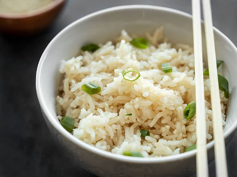 Adding just a few ingredients to your rice can really make your meal pop. Try this Simple Sesame Rice with any of your Southeast Asian inspired meals. BudgetBytes.com Close up side view of a bowl full of sesame rice garnished with green onions