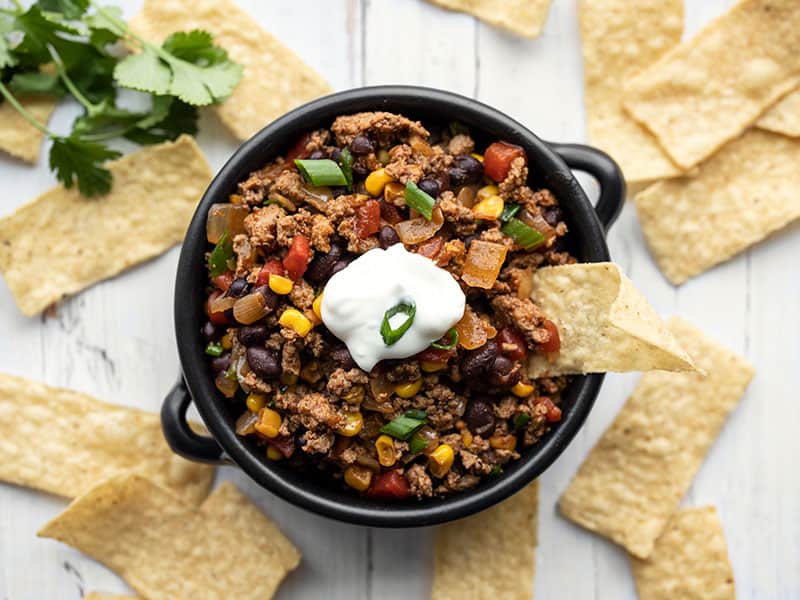 This easy and versatile Turkey Taco Skillet takes about 20 minutes to make, is freezer friendly, and can be served several different ways. BudgetBytes.com Turkey taco skillet in a small bowl with tortilla chips for dipping