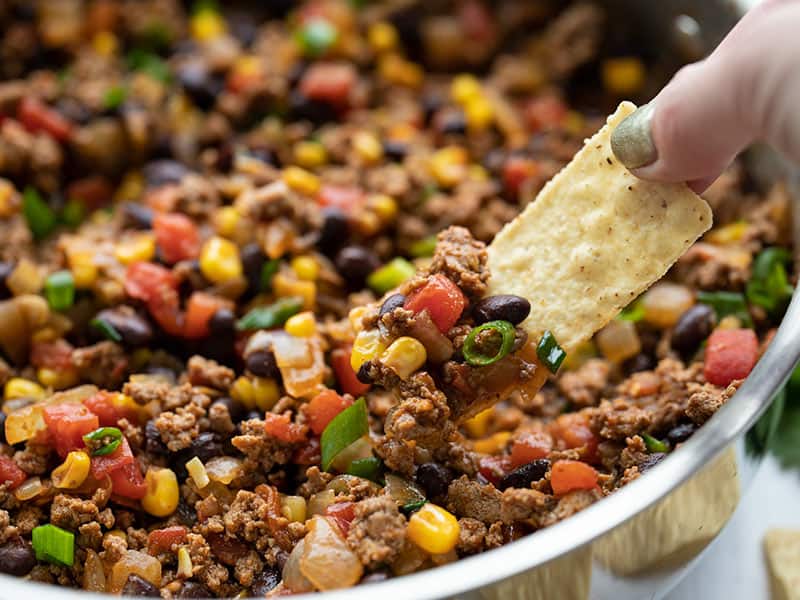 This easy and versatile Turkey Taco Skillet takes about 20 minutes to make, is freezer friendly, and can be served several different ways. BudgetBytes.com Close up of some turkey taco skillet being scooped up by a tortilla chip