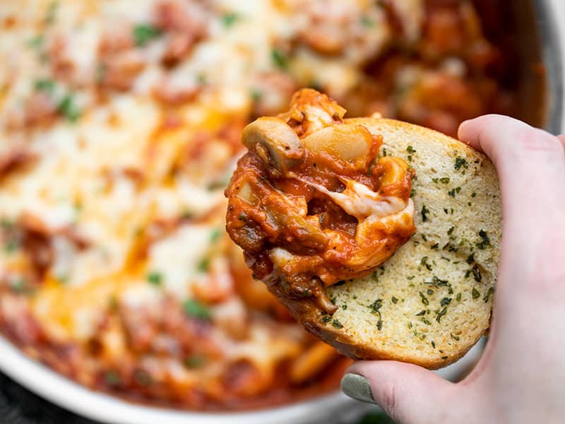 White beans make a fiber-filled swap for gnocchi in this cheesy, indulgent skillet full of white beans, mushrooms, and marinara. BudgetBytes.com Close up of a piece of garlic bread dipped in white beans with mushrooms and marinara