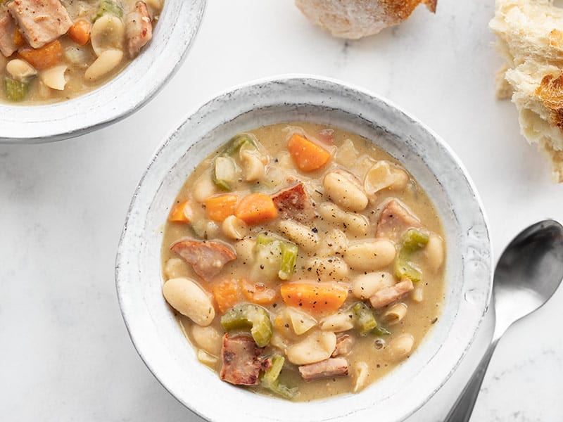 This incredibly easy and deliciously chunky Ham and Bean Soup features a medley of colorful vegetables, browned ham, and plenty of hearty white beans. BudgetBytes.com Two bowls of chunky ham and bean soup with chunks of bread on the side