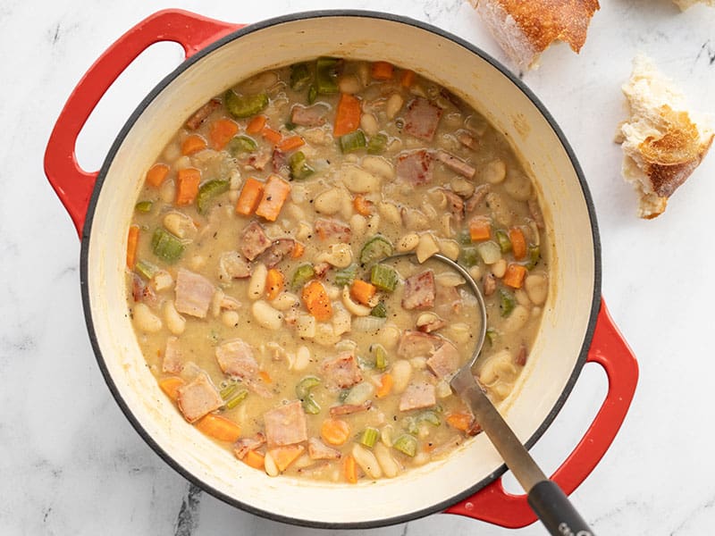 This incredibly easy and deliciously chunky Ham and Bean Soup features a medley of colorful vegetables, browned ham, and plenty of hearty white beans. BudgetBytes.com Finished chunky ham and bean soup in the soup pot with bread on the side