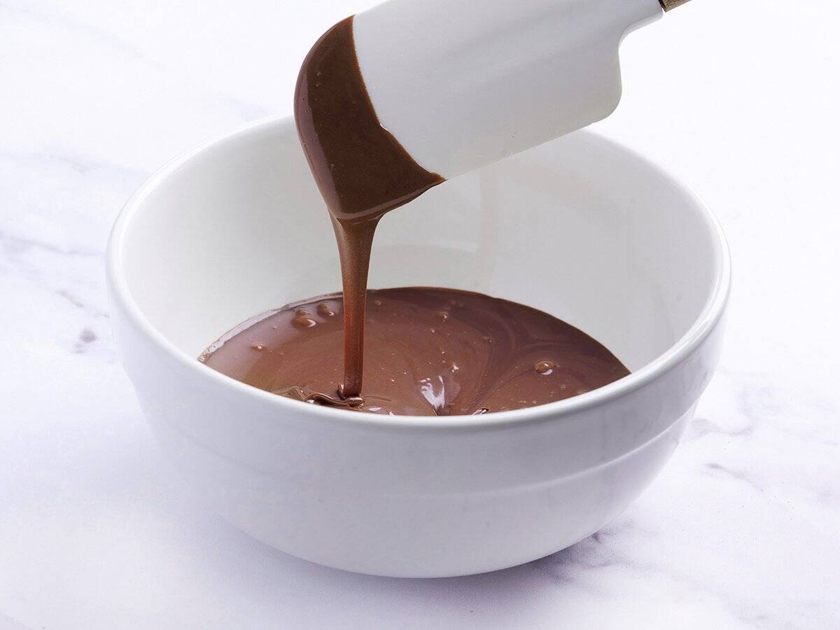 A spatula dipped in a bowl of chocolate icing.