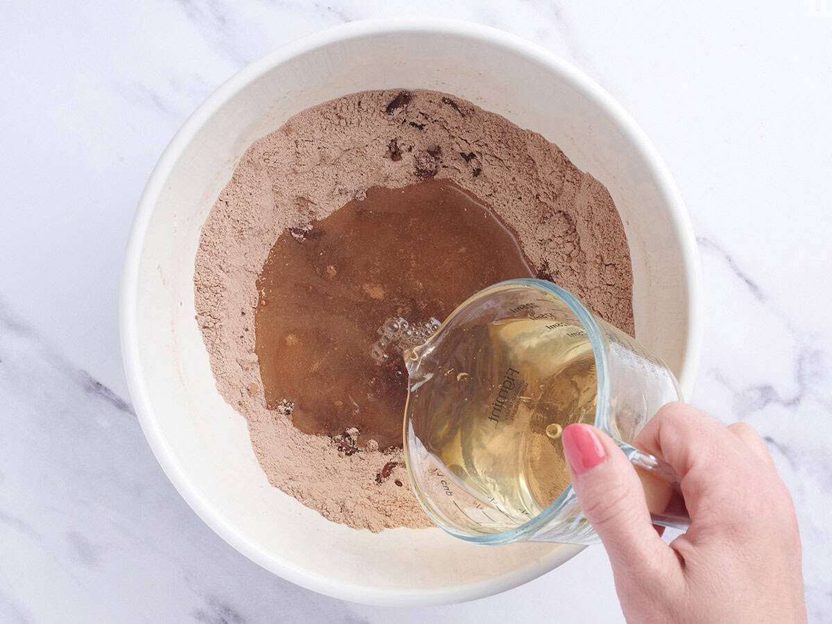 Oil being poured into a flour and chocolate powder mix in a bowl.