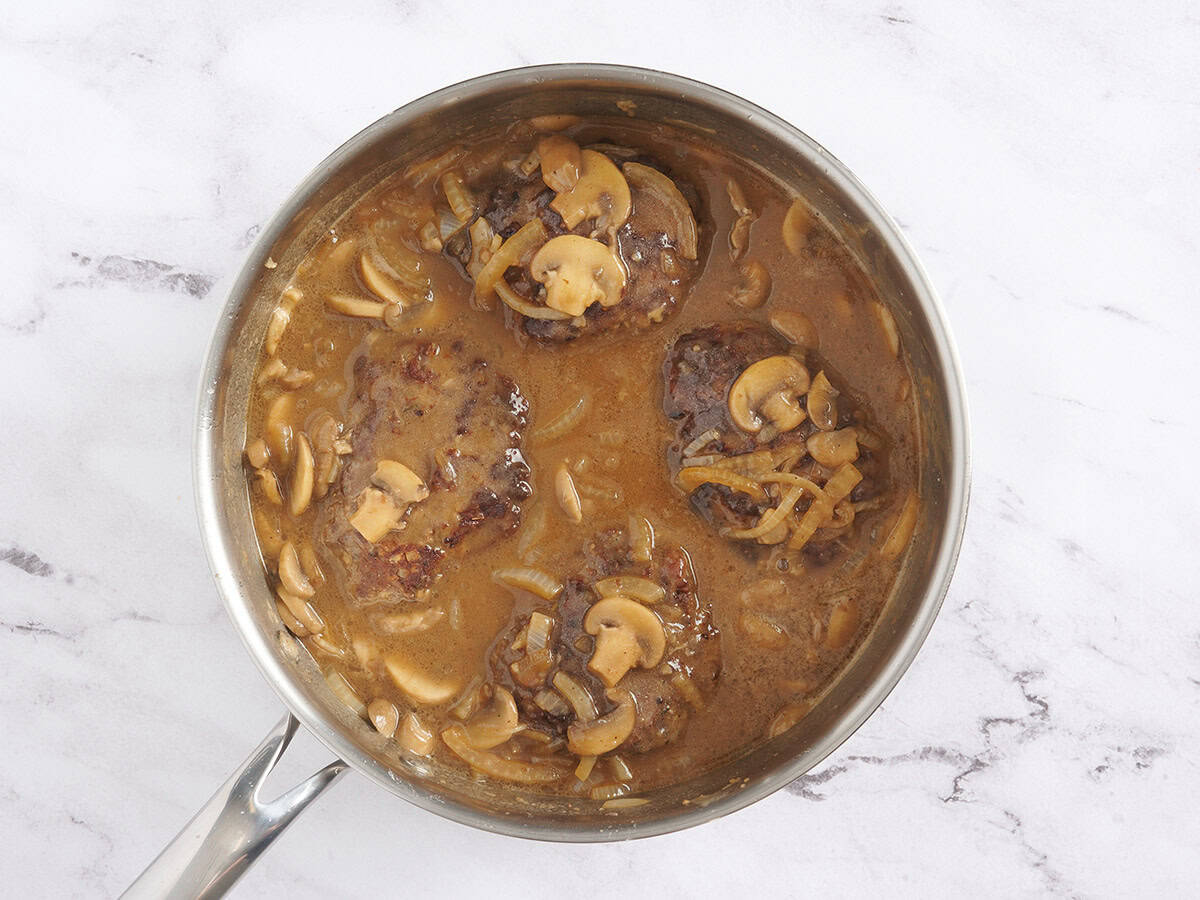 Finished Salisbury steak with mushroom gravy in a skillet.