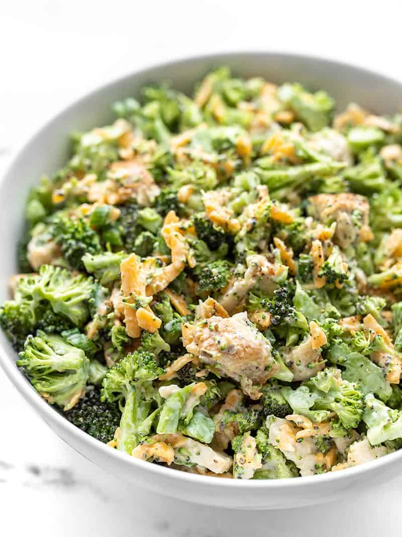 This chunky chopped Broccoli Cheddar Chicken Salad is a great fresh salad that can be eaten on its own or turned into several different easy lunch ideas! BudgetBytes.com Close up side view of a bowl of broccoli cheddar chicken salad with freshly cracked pepper on top