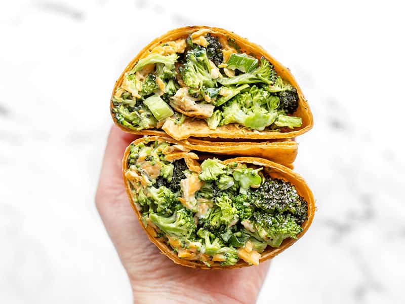 This chunky chopped Broccoli Cheddar Chicken Salad is a great fresh salad that can be eaten on its own or turned into several different easy lunch ideas! BudgetBytes.com Broccoli Cheddar Chicken Salad in a wrap sandwich, open and facing the camera close up