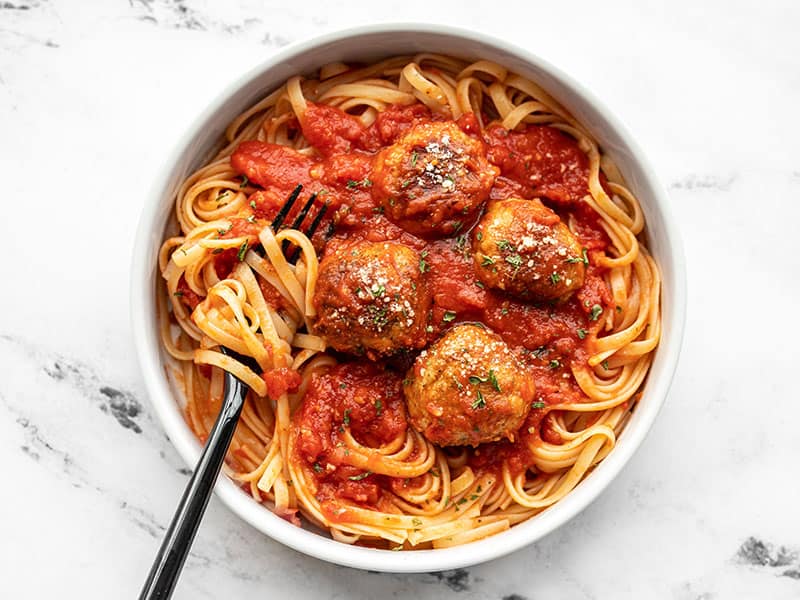 This simple recipe for Chicken Parmesan Meatballs is an easy weeknight dinner win! Swap out any ground meat you have for a quick and delicious dinner. BudgetBytes.com A bowl full of spaghetti with sauce and Chicken Parmesan Meatballs, with a fork in the side.