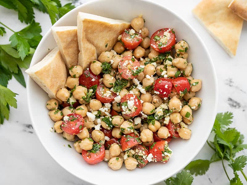 This super simple chickpea salad is bright and flavorful thanks to homemade chimichurri and feta. Goes great with all your summer grilling! BudgetBytes.com Overhead view of a bowl of Chimichurri Chickpea Salad with pita in the side of the bowl