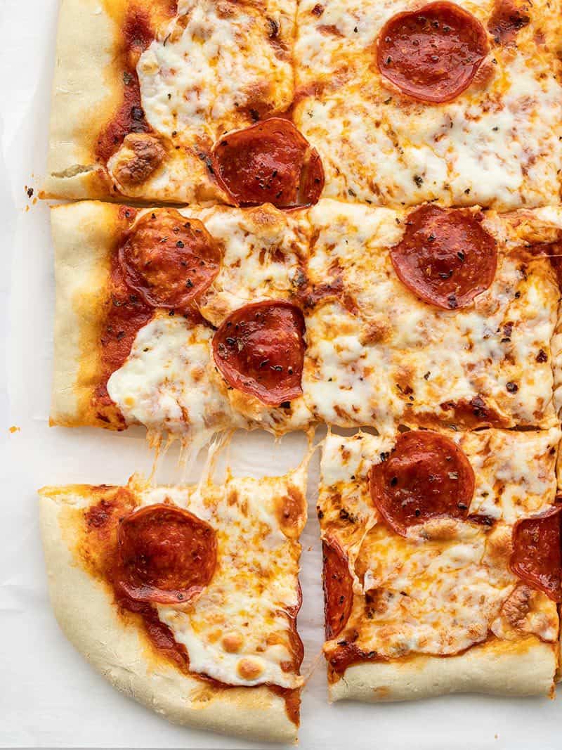 This quick and easy no yeast pizza dough only takes 15 minutes to make and is a great substitute for the classic when ingredients are in short supply. BudgetBytes.com Overhead view of a rectangular pepperoni pizza with the corner piece being pulled out.