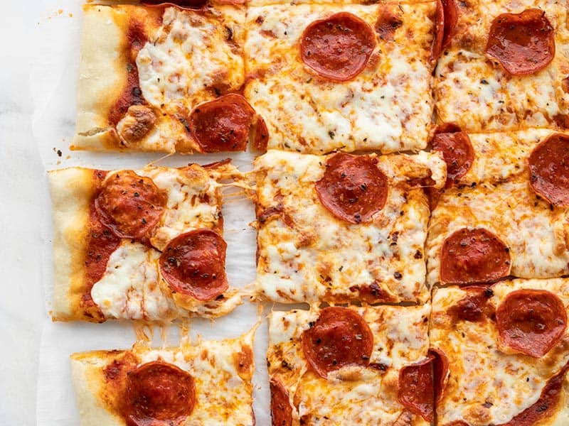 This quick and easy no yeast pizza dough only takes 15 minutes to make and is a great substitute for the classic when ingredients are in short supply. BudgetBytes.com Piece of pepperoni pizza being pulled out the side of the pizza