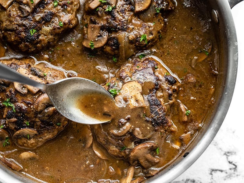 Homemade Salisbury Steak with a rich mushroom gravy is a quick, simple, and hearty weeknight dinner that will fill even the biggest of appetites! BudgetBytes.com Gravy being spooned over a Salisbury Steak in the skillet