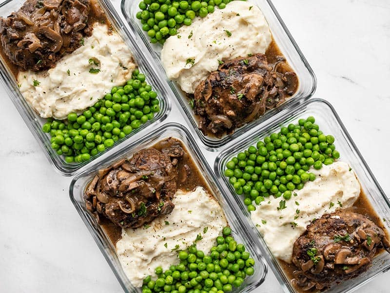 Homemade Salisbury Steak with a rich mushroom gravy is a quick, simple, and hearty weeknight dinner that will fill even the biggest of appetites! BudgetBytes.com Salisbury Steak in rectangular meal prep containers with mashed potatoes and peas