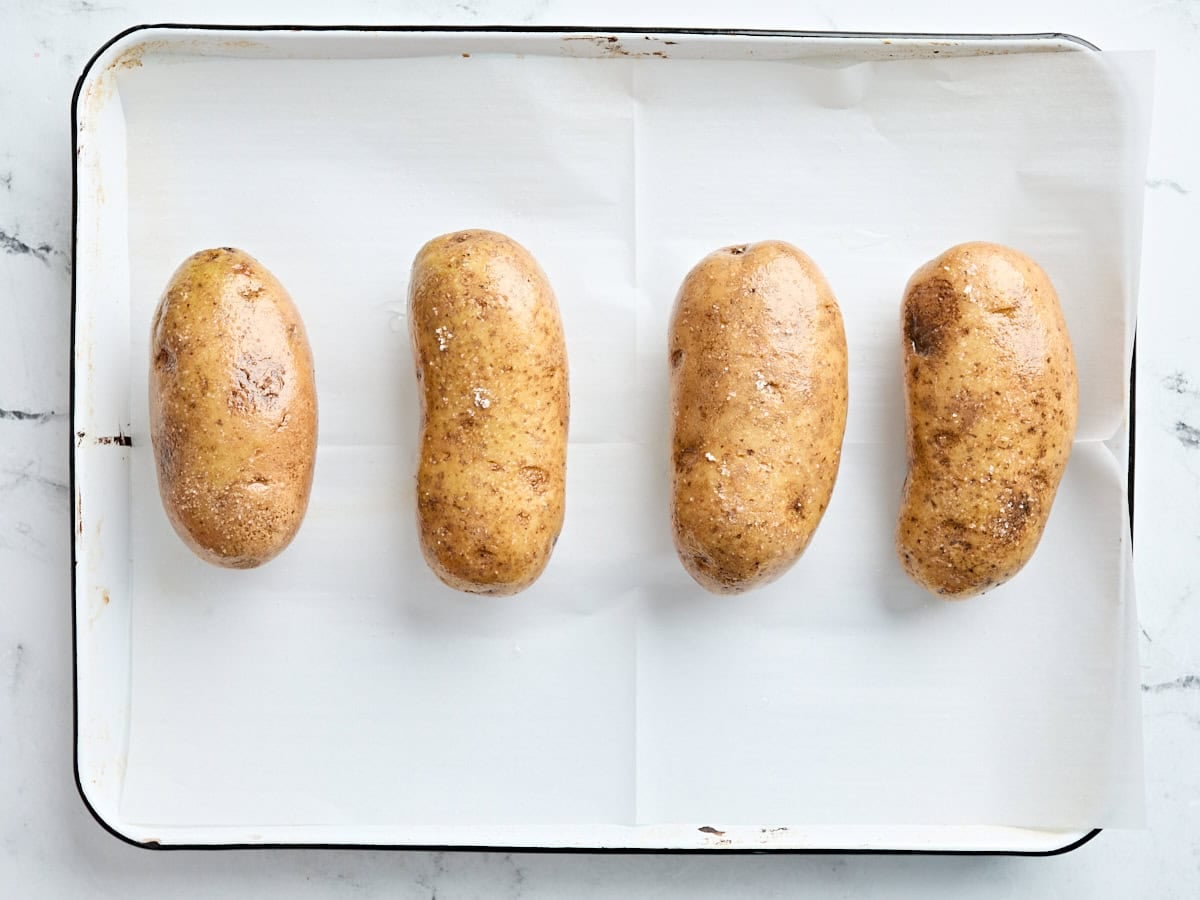 Seasoned potatoes on a parchment lined baking sheet.