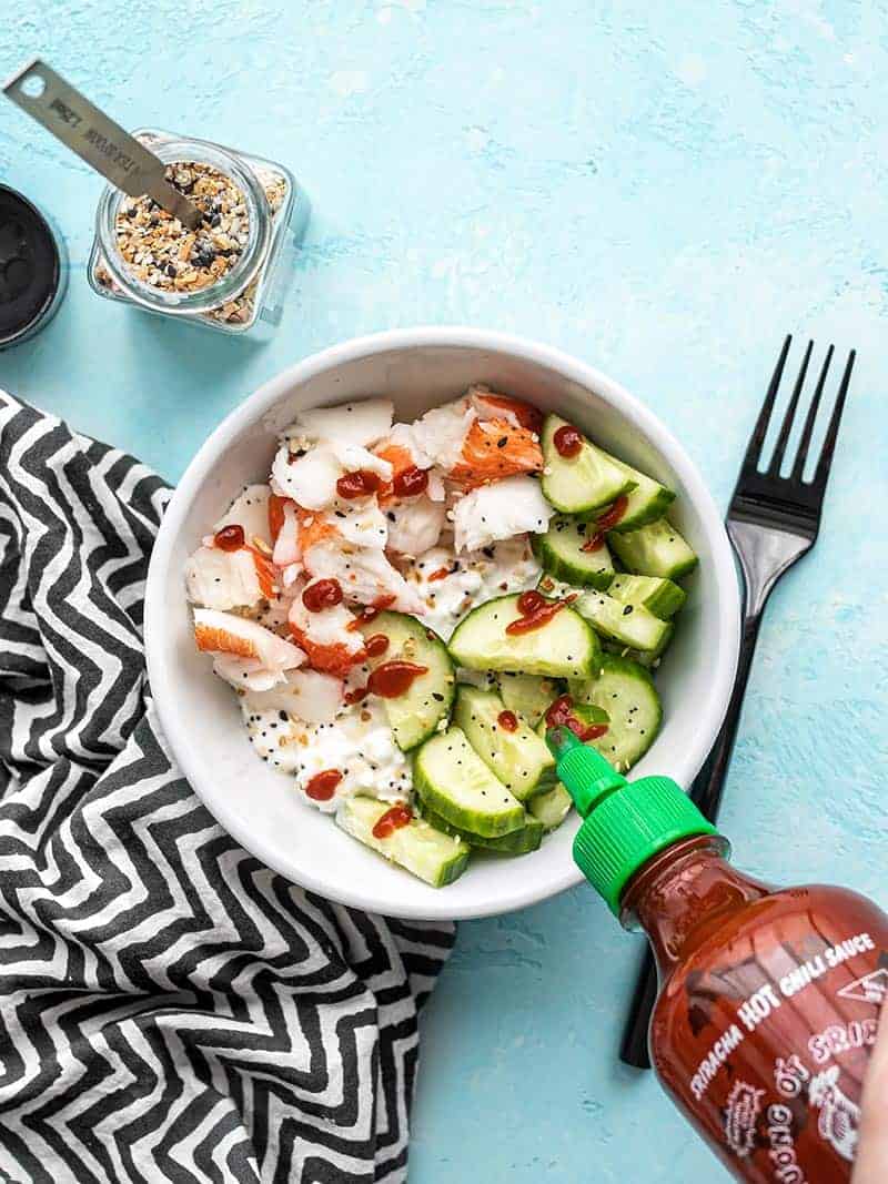 This Cottage Cheese Crab Bowl is the perfect light, fresh, and filling lunch for summer. It also meal preps well, so pack a few to take to work for lunch! Budetbytes.com Sriracha being drizzled onto a cottage cheese crab bowl, from above