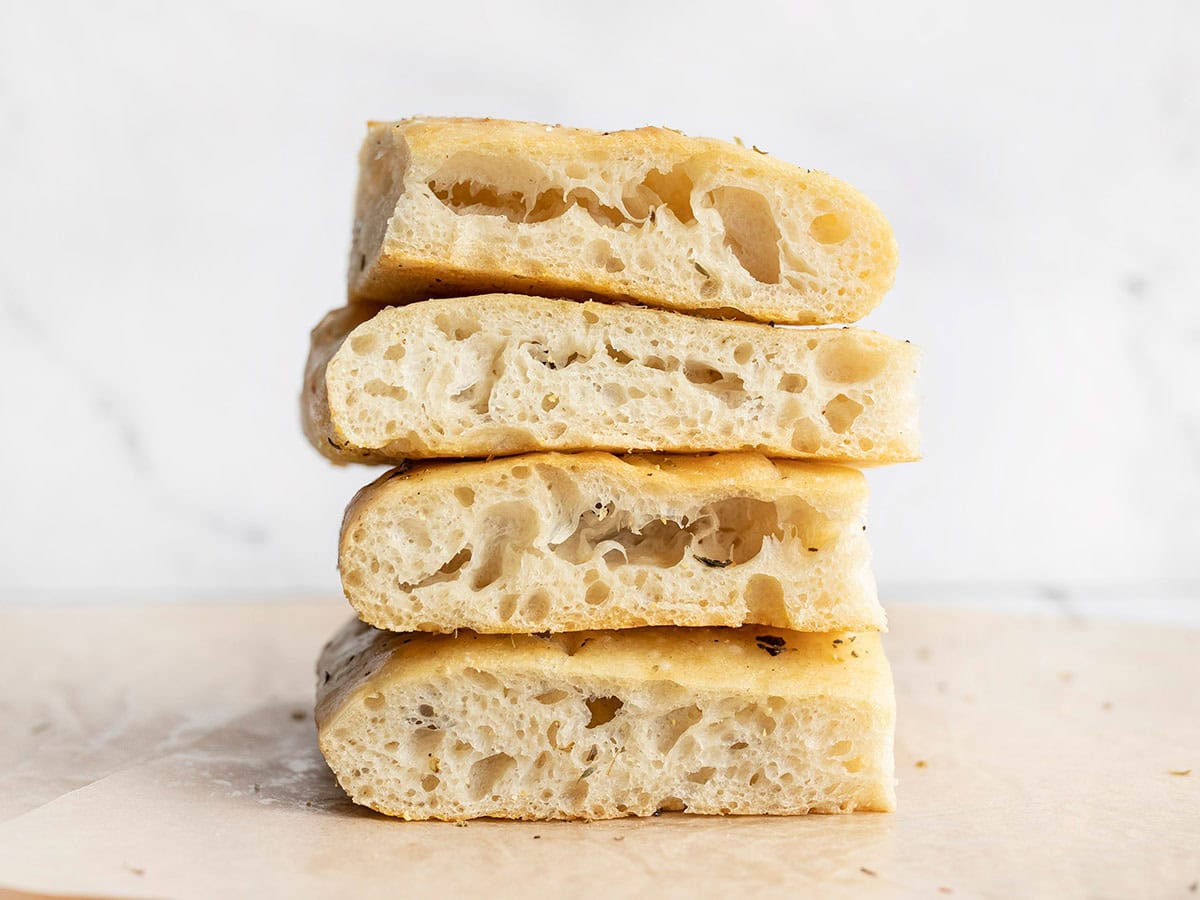 A stack of slices of no knead focaccia bread showing off large bubbles.