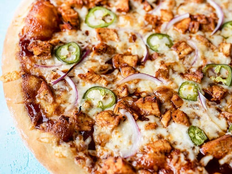 Get the classic BBQ Chicken Pizza recipe, plus other fun toppings you can add that pair well with BBQ and make your pizza even more flavorful. Budgetbytes.com Close up side view of a BBQ Chicken Pizza