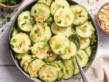 Overhead view of a bowl of sesame cucumber salad with a spoon.