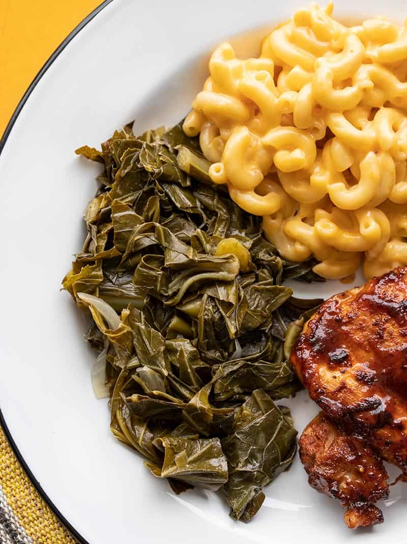 Sweet, spicy, and savory, these Jerk Seasoned Collard Greens are a hearty and flavorful side dish that also makes great leftovers! Budgetbytes.com Collard Greens on a plate with Mac and Cheese and BBQ Chicken