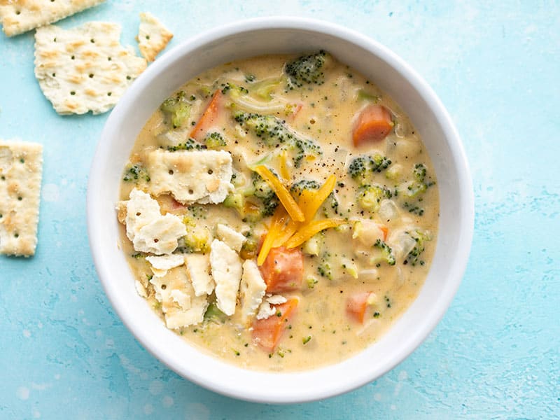 This super easy Broccoli Cheddar Soup is chock full of colorful, chunky vegetables in a rich and cheesy broth for a totally meal-worthy soup. Budgetbytes.com Overhead view of a bowl of broccoli cheddar soup with saltine crackers