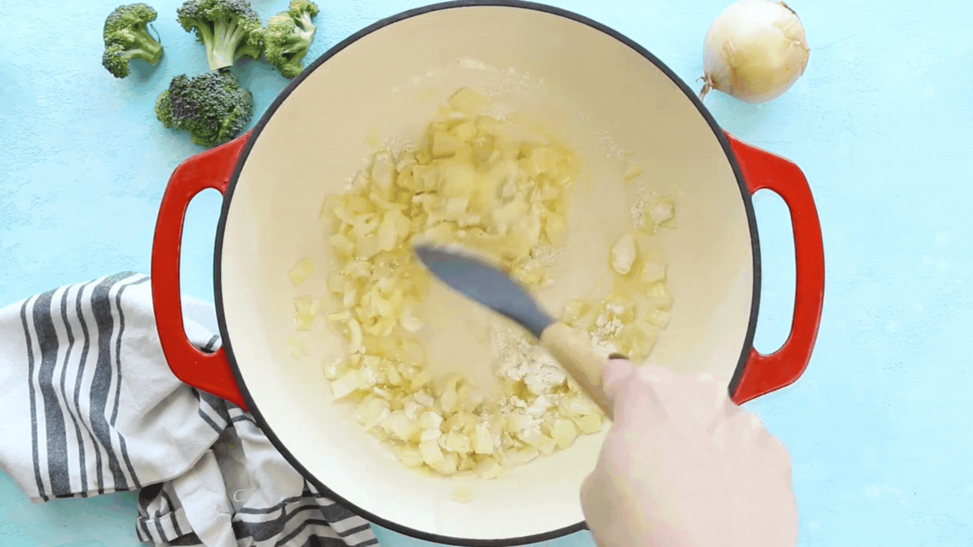 A video GIF showing chicken broth being mixed into sauteed onion.