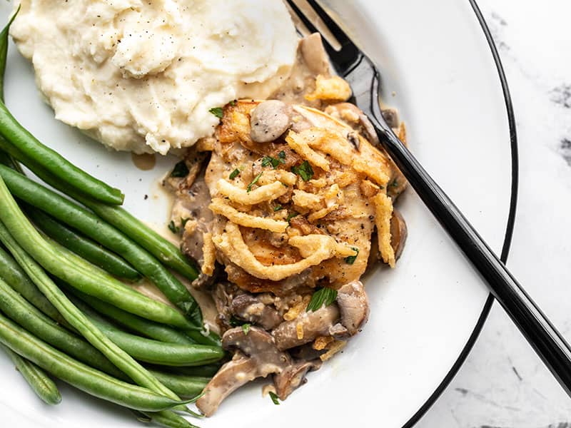 Creamy Mushroom Chicken topped with delicious crispy onions is an easy weeknight dinner with plenty of options for customization! Budgetbytes.com Creamy mushroom chicken on a plate with mashed potatoes and green beans