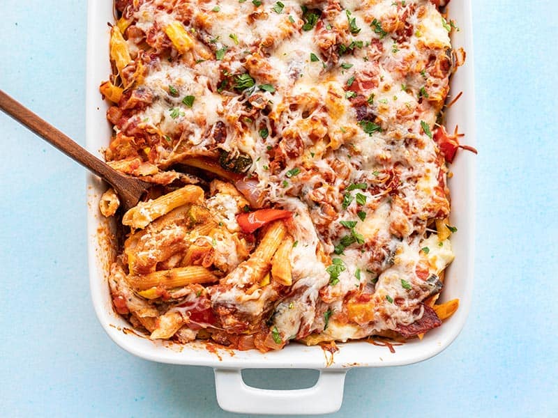 Layers of pasta, flavorful roasted vegetables, a simple homemade red sauce, and melty cheese make this roasted vegetable baked penne to die for! Budgetbytes.com Overhead view of roasted vegetable baked penne being scooped out of the casserole dish