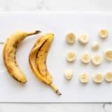 A close-up of freshly sliced bananas arranged neatly on a wooden cutting board.