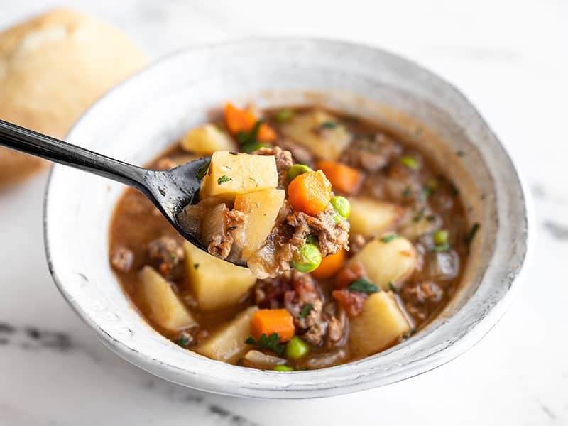 This super easy Slow Cooker Hamburger Stew is simple, comforting food at its best. And the leftovers are even better the next day! Budgetbytes.com Slow Cooker Hamburger stew in a bowl with a spoon lifting a bite